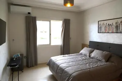 a bedroom with a large bed and a window at Golf Royal appartement in Fès
