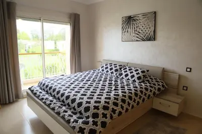 a bedroom with a black and white bed with a window at Golf Royal appartement in Fès