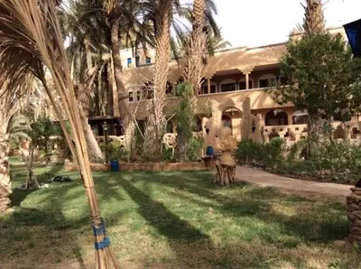 a large house with palm trees in the yard at Gite D'Etape Amced in Goulmima