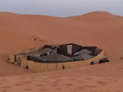 a man in the desert with a tent in the desert at Gite D'Etape Amced in Goulmima