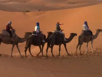 a group of people riding on camels in the desert at Gite D'Etape Amced in Goulmima