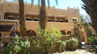 a building with palm trees in front of it at Gite D'Etape Amced in Goulmima