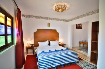a bedroom with a large bed with a wooden headboard at Riad Dari Fes in Fès