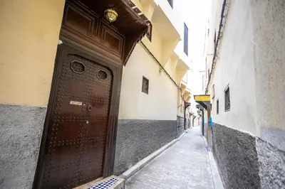 an alley with a brown door on a building at Riad Dari Fes in Fès