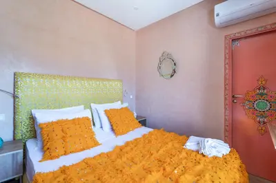 a bedroom with a bed with orange sheets and pillows at Riad Les Nuits De Fès in Fès