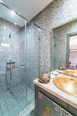 a bathroom with a glass shower and a sink at Riad Les Nuits De Fès in Fès