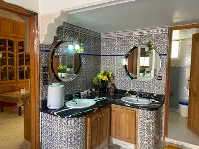 a bathroom with two sinks and two mirrors at Appartement Villa Rayhana in Khenifra