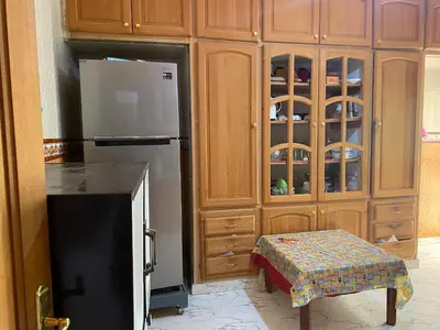 a kitchen with a refrigerator and some wooden cabinets at Appartement Villa Rayhana in Khenifra