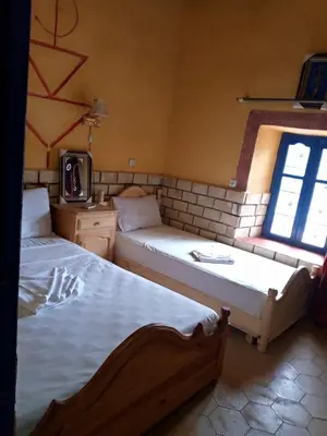 a bedroom with two beds and a window at Les Pyramides Hotel Merzouga in Merzouga
