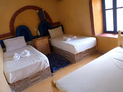 a room with three beds in a room at Les Pyramides Hotel Merzouga in Merzouga