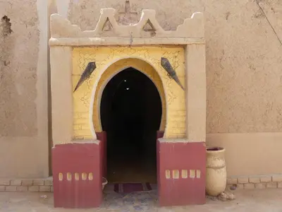 a red and yellow door in the side of a building at Les Pyramides Hotel Merzouga in Merzouga