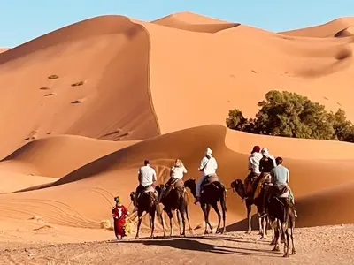 a group of people riding horses in the desert at Les Pyramides Hotel Merzouga in Merzouga