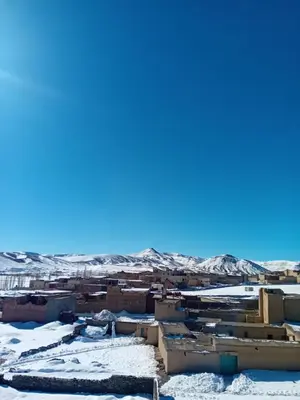 a city covered in snow with mountains in the background at Auberge Chez Bassou Agoudal in Agoudal