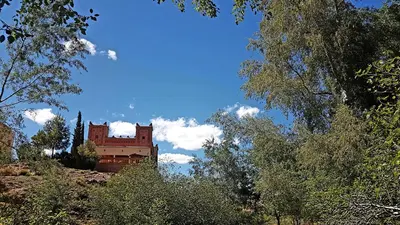 a building sitting on top of a hill with trees at Auberge Kasbah Ait Marghad in Tamellalt