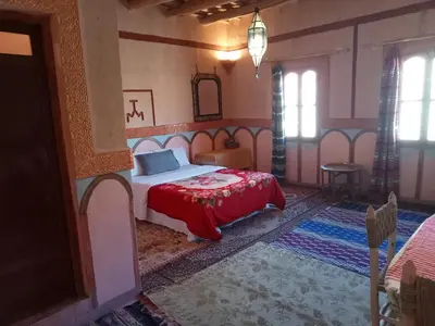 a bedroom with a bed with a red blanket at Auberge Kasbah Ait Marghad in Tamellalt