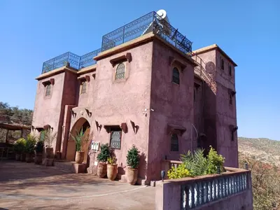a large red brick building with potted plants on it at Riad Heermans in Ouzoud