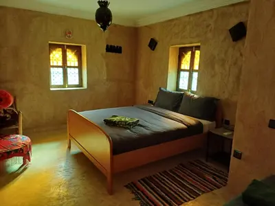 a bedroom with a bed and two windows at Riad Heermans in Ouzoud