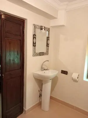 a bathroom with a sink and a mirror and a door at Riad Heermans in Ouzoud