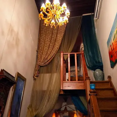 a room with a chandelier and a staircase with curtains at Riad Rchacha in Fès
