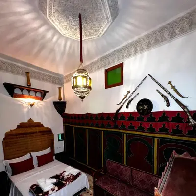 a bedroom with a bed and a chandelier at Riad dar Kirami in Fès