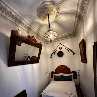 a bedroom with a bed and a mirror and a chandelier at Riad dar Kirami in Fès