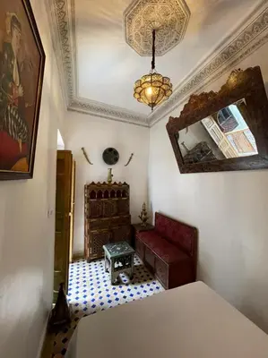 a bedroom with a bed and a chair and a mirror at Riad dar Kirami in Fès