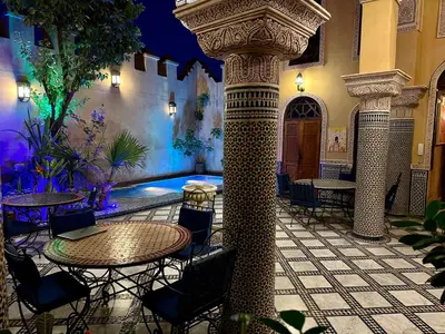 a patio with a table and chairs in a building at Riad Layalina Fes 7 Chambres & 18 Personnes Piscine, Parking, Vue & Wifi au Pied Medina in Fès