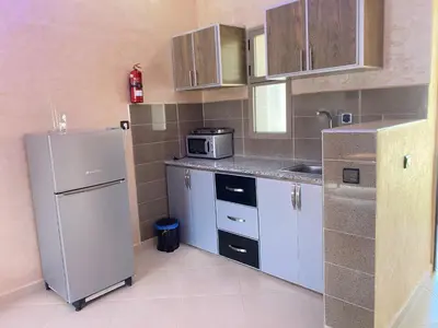 a small kitchen with a refrigerator and a sink at IGHIZ INN resort in Er Rachidia