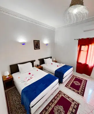 a bedroom with two beds with blue and white sheets at Guest House Qodwa in Marrakech