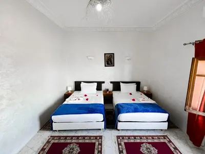 two beds in a room with white walls at Guest House Qodwa in Marrakech