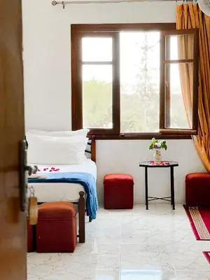 a bedroom with a bed and a window and a table at Guest House Qodwa in Marrakech