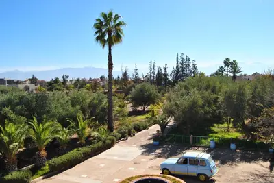 a blue van parked in a parking lot with a palm tree at Guest House Qodwa in Marrakech
