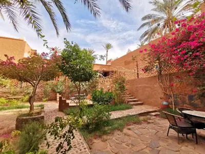 a garden with pink flowers and a table and chairs at Riad Dar Zaouia in Zagora