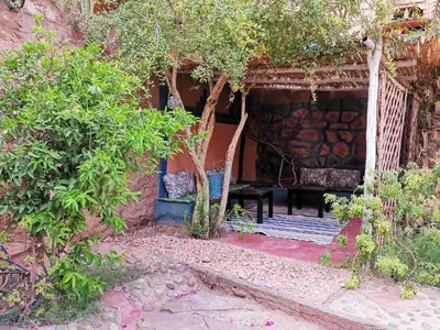 a porch with a bench and trees in a garden at Riad Dar Zaouia in Zagora