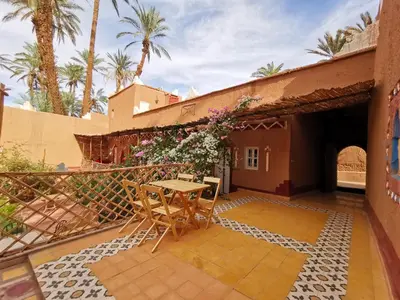 a patio with a table and chairs and palm trees at Riad Dar Zaouia in Zagora