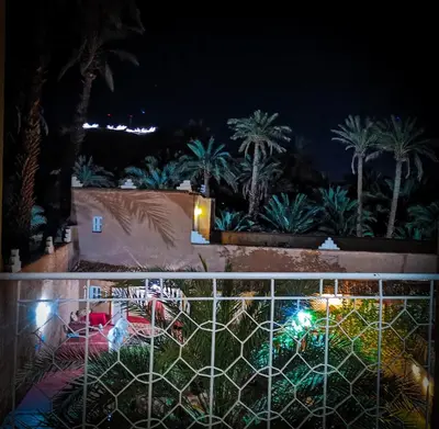 a view of a yard at night with palm trees at Riad Dar Zaouia in Zagora