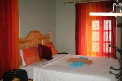 a bedroom with a bed with white sheets and orange curtains at Maggaman Guest House in Tafraoute Sidi Ali