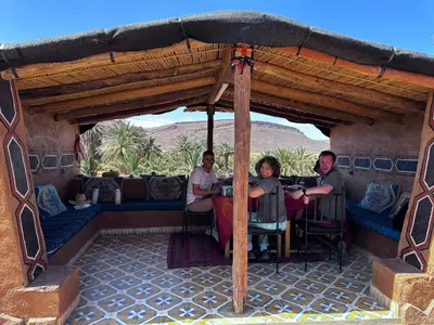 a group of people sitting at a table under an umbrella at Maggaman Guest House in Tafraoute Sidi Ali
