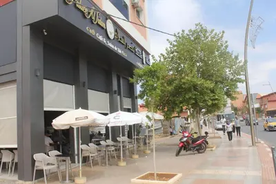 a restaurant with tables and umbrellas on a city street at HOTEL CAFE PALAIS SALAM , Beni Mellal in Beni Mellal