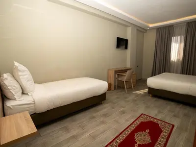 a hotel room with two beds and a table at HOTEL CAFE PALAIS SALAM , Beni Mellal in Beni Mellal
