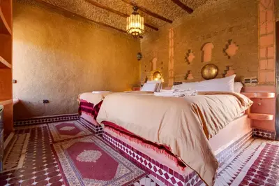 a bedroom with two beds and a chandelier at Hotel ksar merzouga in Merzouga