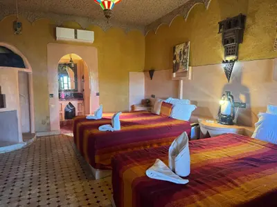 a hotel room with three beds and a bathroom at Hotel ksar merzouga in Merzouga