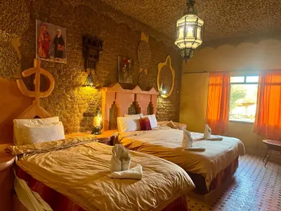 a bedroom with two beds and a chandelier at Hotel ksar merzouga in Merzouga