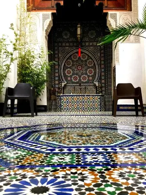 a mosaic floor in front of a wall with two chairs at Dar 7 Louyat in Fès