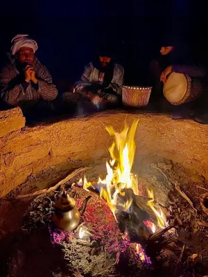 a group of people sitting around a fire at Erg Chegaga Nomad camp in El Gouera