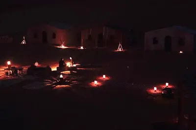 a group of people sitting around a fire pit at night at Erg Chegaga Nomad camp in El Gouera