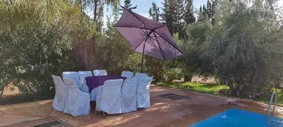 a table and chairs with an umbrella next to a pool at villa Marrakech raja in Marrakech