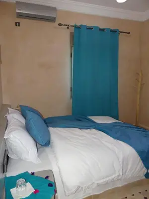 a bedroom with a bed with a blue curtain at Dar Diafa Chez Anaam in Er Rachidia