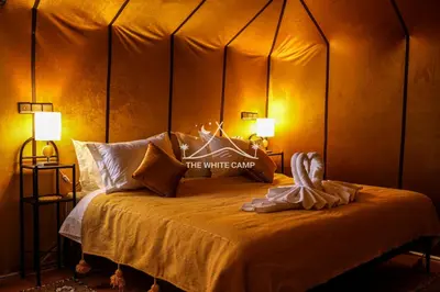 a bedroom with a bed with two lamps on it at Merzouga White Camp - Official Luxury Camp in Merzouga