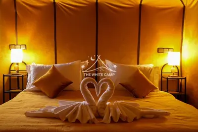 a bed with two white swans making a heart at Merzouga White Camp - Official Luxury Camp in Merzouga